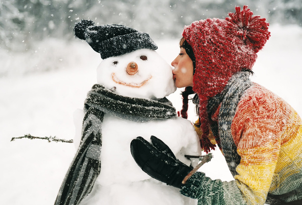 девушка в шапке целует снеговика, фото